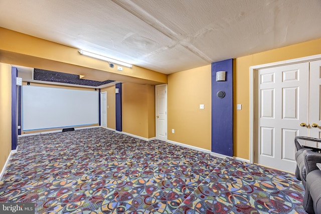 carpeted home theater room featuring a textured ceiling and baseboards