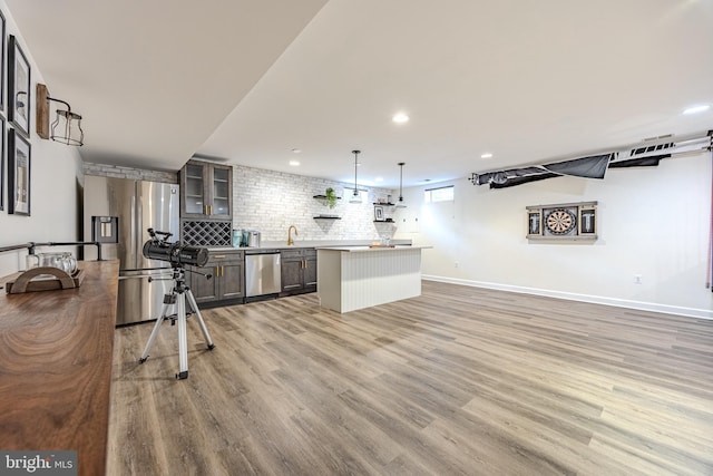 kitchen with recessed lighting, glass insert cabinets, light wood-style flooring, stainless steel appliances, and a kitchen island