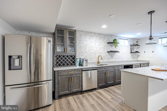 kitchen featuring open shelves, a sink, appliances with stainless steel finishes, light countertops, and light wood finished floors