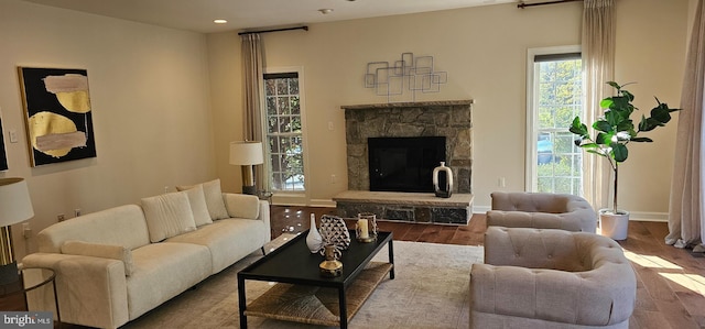 living area featuring baseboards, recessed lighting, wood finished floors, and a fireplace