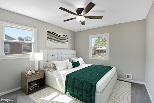 carpeted bedroom featuring baseboards, a ceiling fan, and visible vents