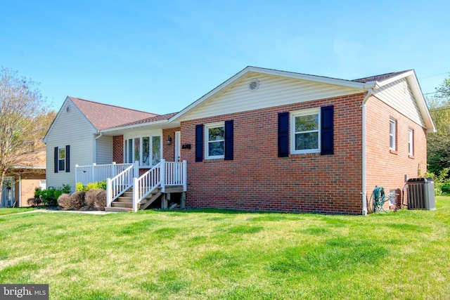 ranch-style house featuring brick siding, central AC, and a front yard