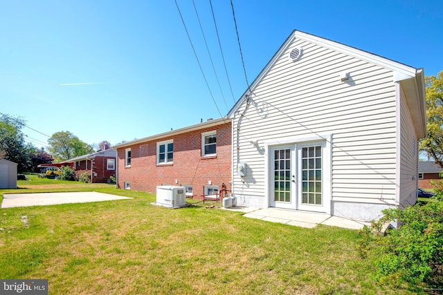 rear view of house featuring a yard, brick siding, and french doors
