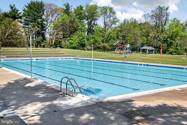 community pool featuring a yard and playground community