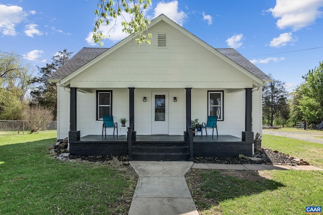 bungalow featuring concrete block siding, roof with shingles, a porch, and a front yard