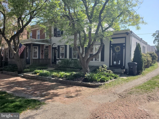view of front of property featuring brick siding, a porch, and stucco siding