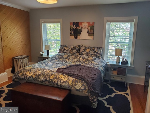 bedroom with wooden walls, wood finished floors, and baseboards