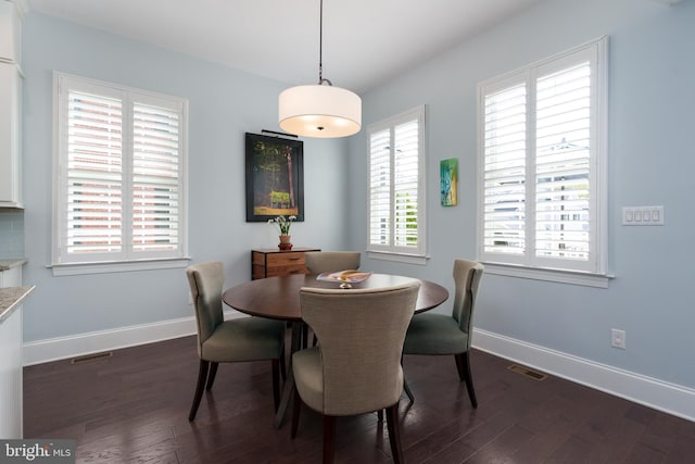 dining area featuring dark wood-style flooring, baseboards, and visible vents