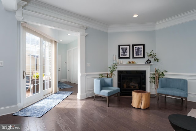 sitting room featuring wood finished floors, a wainscoted wall, a glass covered fireplace, ornamental molding, and recessed lighting