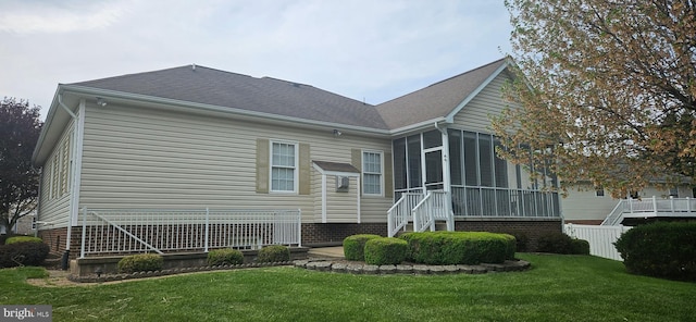 rear view of property with a yard, a sunroom, a shingled roof, and fence
