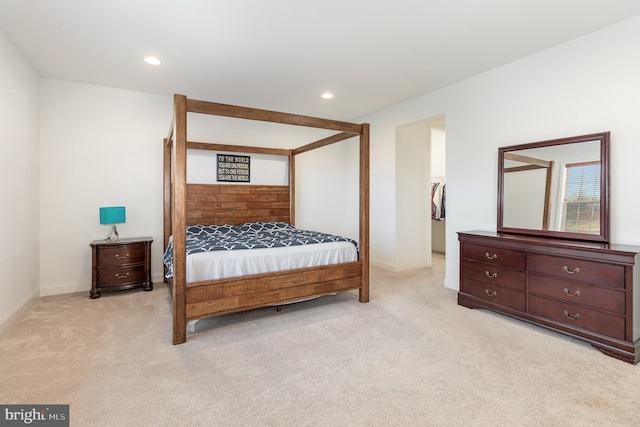 bedroom with light colored carpet, baseboards, a walk in closet, and recessed lighting