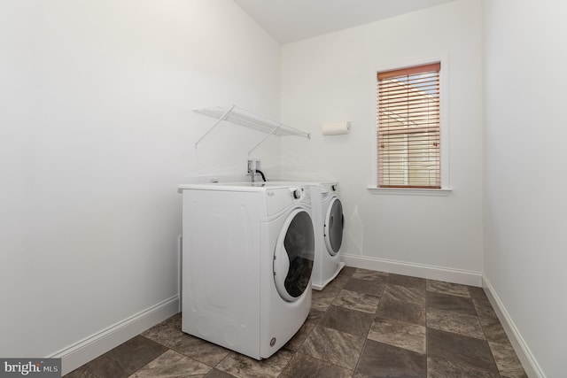 laundry area featuring stone finish flooring, baseboards, washer and clothes dryer, and laundry area