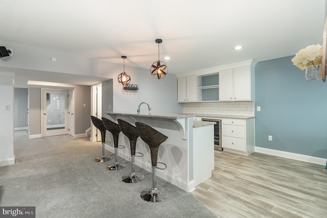 kitchen with white cabinets, wine cooler, a breakfast bar, open shelves, and light stone countertops