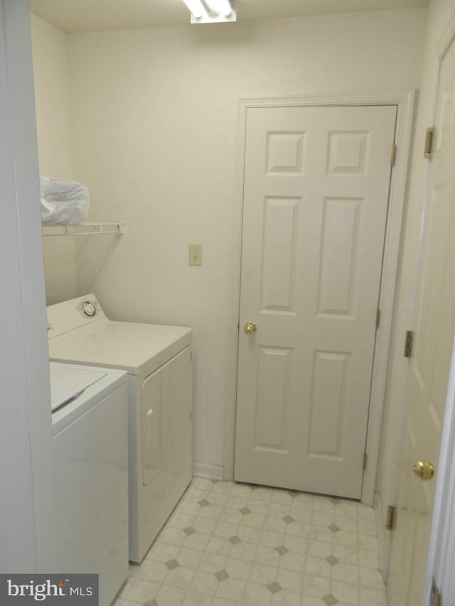 clothes washing area with separate washer and dryer, light floors, and laundry area