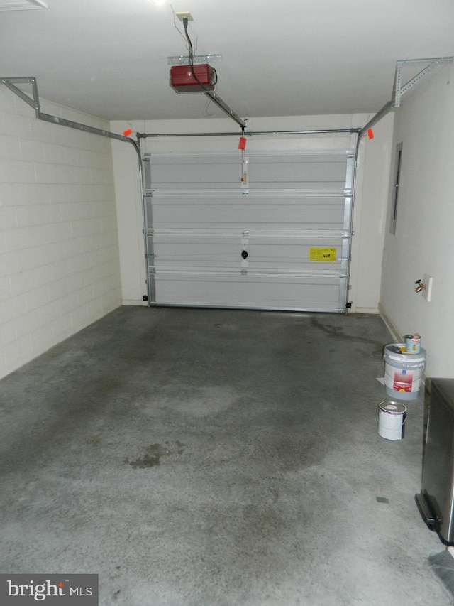 garage with a garage door opener, electric panel, and concrete block wall