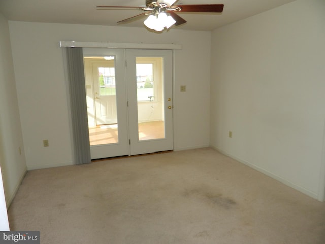 unfurnished room with ceiling fan, light carpet, and baseboards