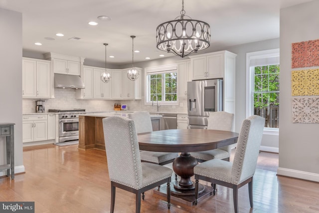 dining area with a chandelier, light wood-style flooring, baseboards, and recessed lighting