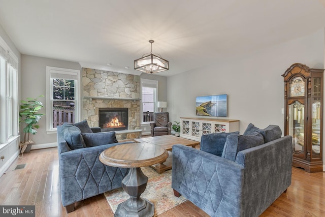 living room featuring a fireplace, wood finished floors, visible vents, and baseboards