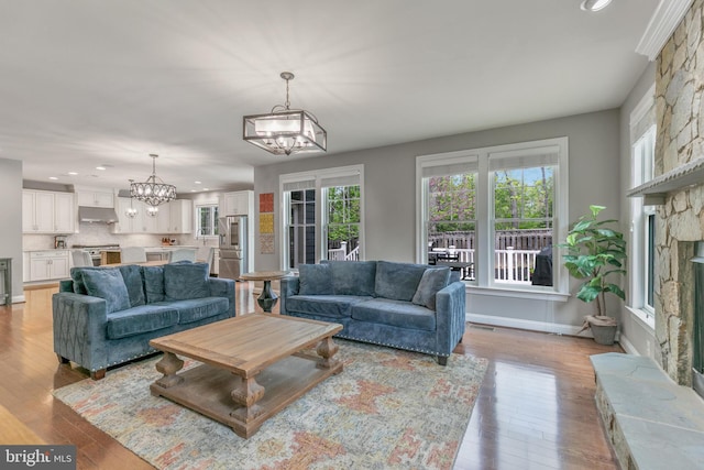 living room with recessed lighting, light wood-style flooring, baseboards, and an inviting chandelier