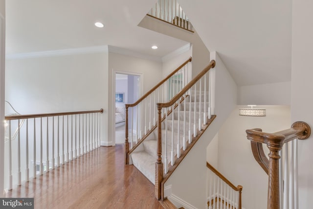 stairs with recessed lighting, wood finished floors, baseboards, and ornamental molding