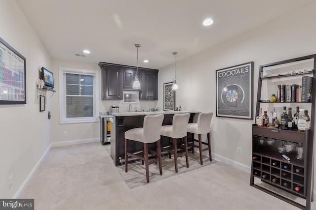 kitchen with baseboards, light carpet, pendant lighting, and a breakfast bar area