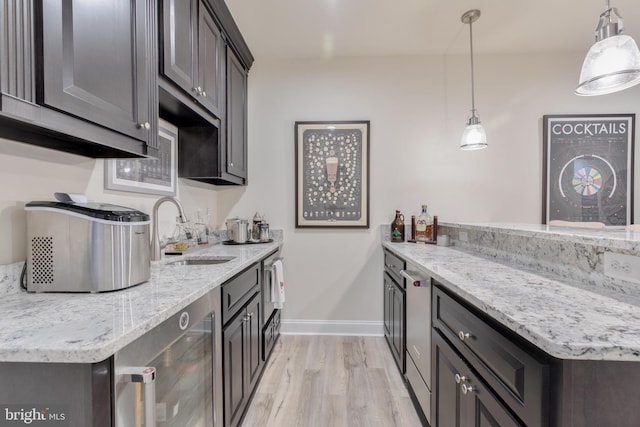 kitchen with a sink, light wood finished floors, baseboards, a peninsula, and light stone countertops