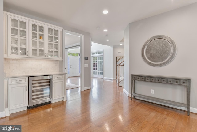 bar with baseboards, light wood finished floors, and wine cooler