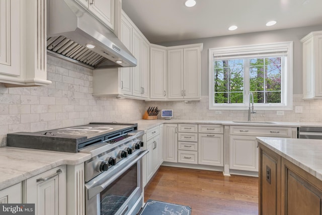 kitchen with a sink, appliances with stainless steel finishes, white cabinets, backsplash, and under cabinet range hood