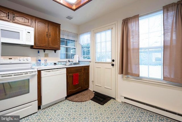 kitchen featuring a baseboard radiator, white appliances, light countertops, a healthy amount of sunlight, and light floors