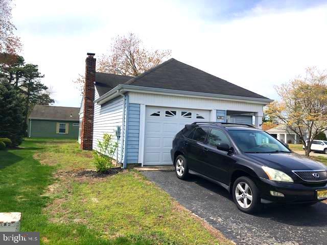 view of side of property with a yard, an attached garage, a chimney, and aphalt driveway