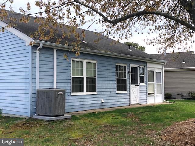 rear view of house featuring a lawn and central air condition unit