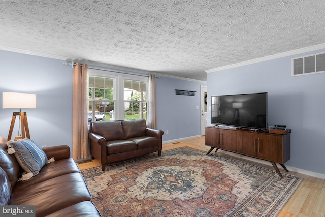 living area with ornamental molding, light wood-type flooring, a textured ceiling, and baseboards