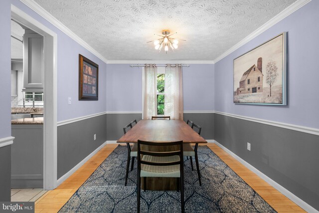 dining room with light wood-style flooring, a chandelier, baseboards, and crown molding