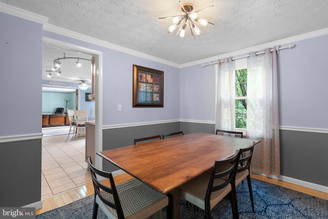 dining space with a ceiling fan, a textured ceiling, light wood finished floors, baseboards, and crown molding