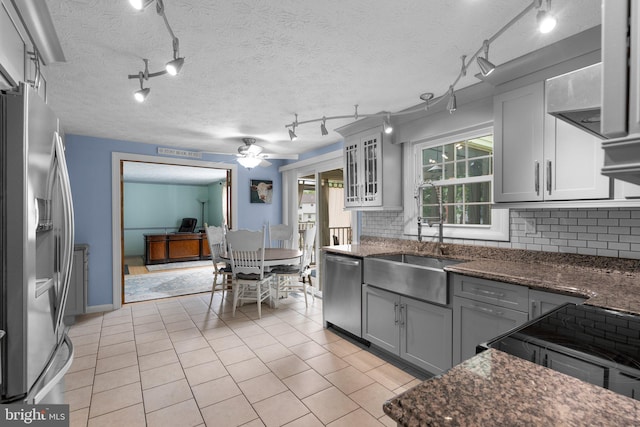 kitchen with track lighting, appliances with stainless steel finishes, a sink, tasteful backsplash, and a textured ceiling