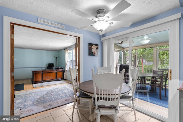 dining area with a textured ceiling, ceiling fan, and tile patterned floors