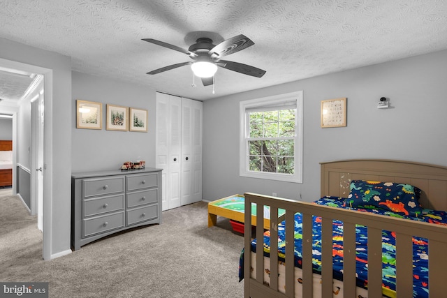 bedroom with carpet, a closet, a textured ceiling, and a ceiling fan