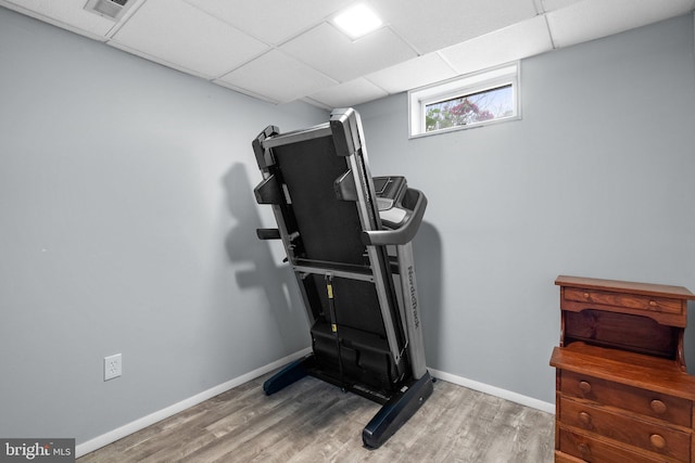 workout room with wood finished floors, baseboards, and a drop ceiling