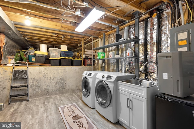 clothes washing area with independent washer and dryer, cabinet space, and light wood-style floors