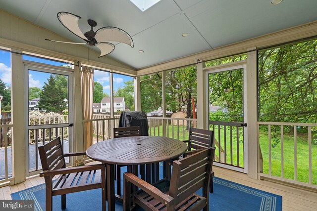 sunroom / solarium with a ceiling fan, outdoor dining area, vaulted ceiling, and a skylight