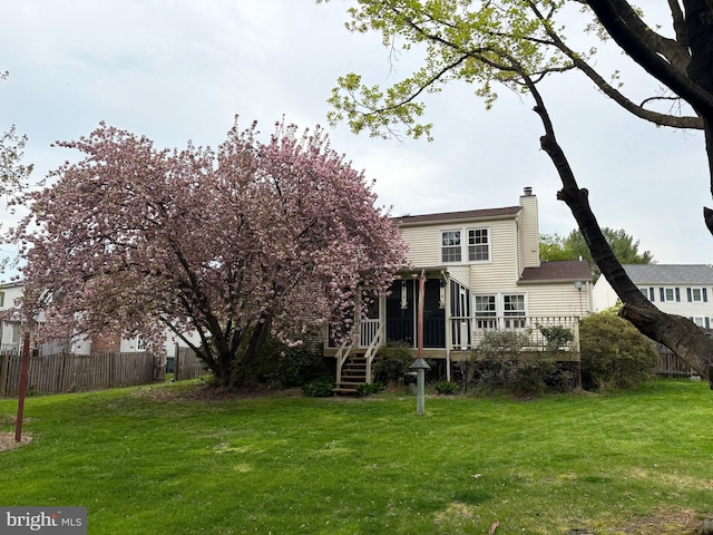 back of property with a sunroom, a chimney, and a wooden deck