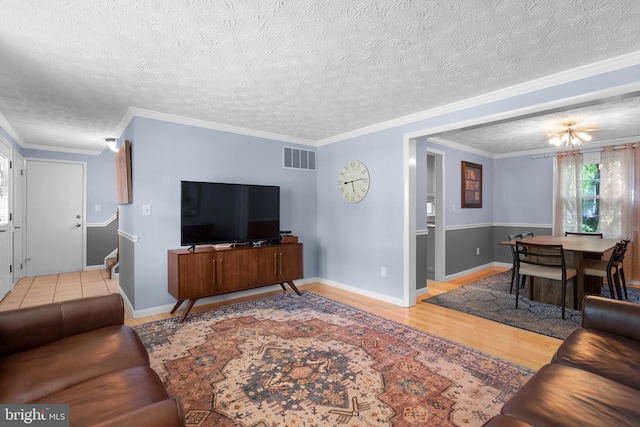 living area featuring wood finished floors, stairway, crown molding, baseboards, and a textured ceiling
