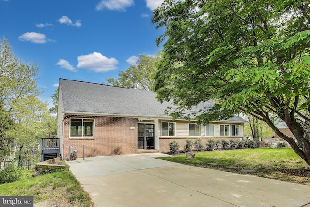 single story home with brick siding, roof with shingles, a front yard, and concrete driveway