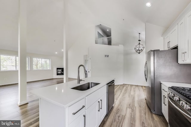 kitchen with a sink, appliances with stainless steel finishes, high vaulted ceiling, and light countertops