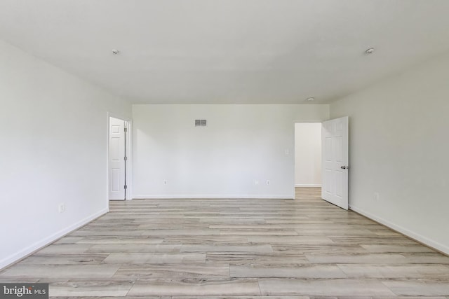 spare room with baseboards, light wood-type flooring, and visible vents