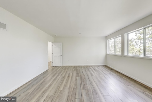 unfurnished room featuring baseboards, light wood finished floors, and visible vents