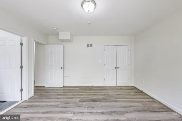 empty room featuring baseboards, light wood-type flooring, and visible vents