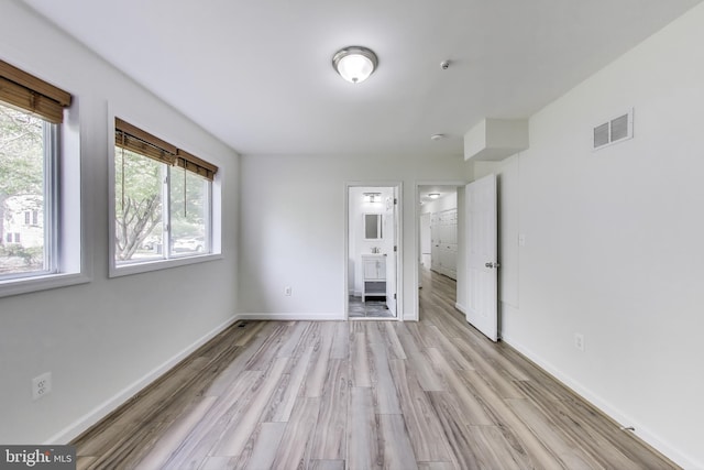 unfurnished bedroom with visible vents, light wood-style floors, ensuite bathroom, and baseboards