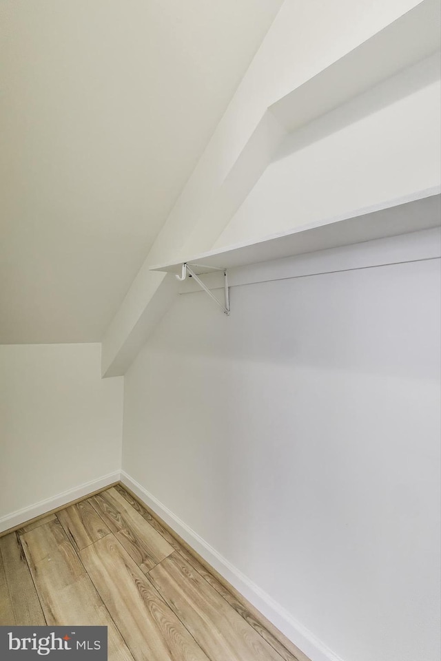 walk in closet featuring vaulted ceiling and light wood-type flooring