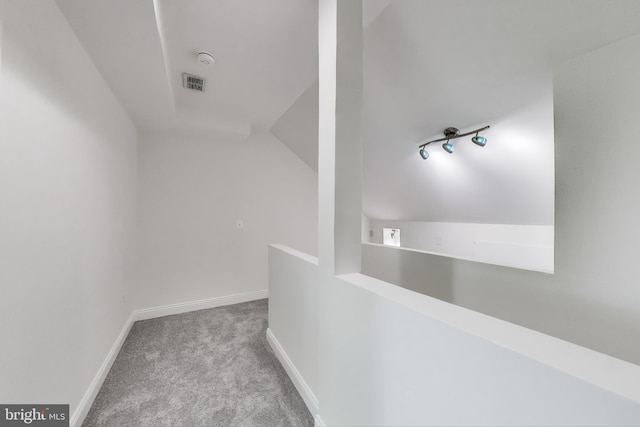 hall featuring baseboards, visible vents, vaulted ceiling, and carpet
